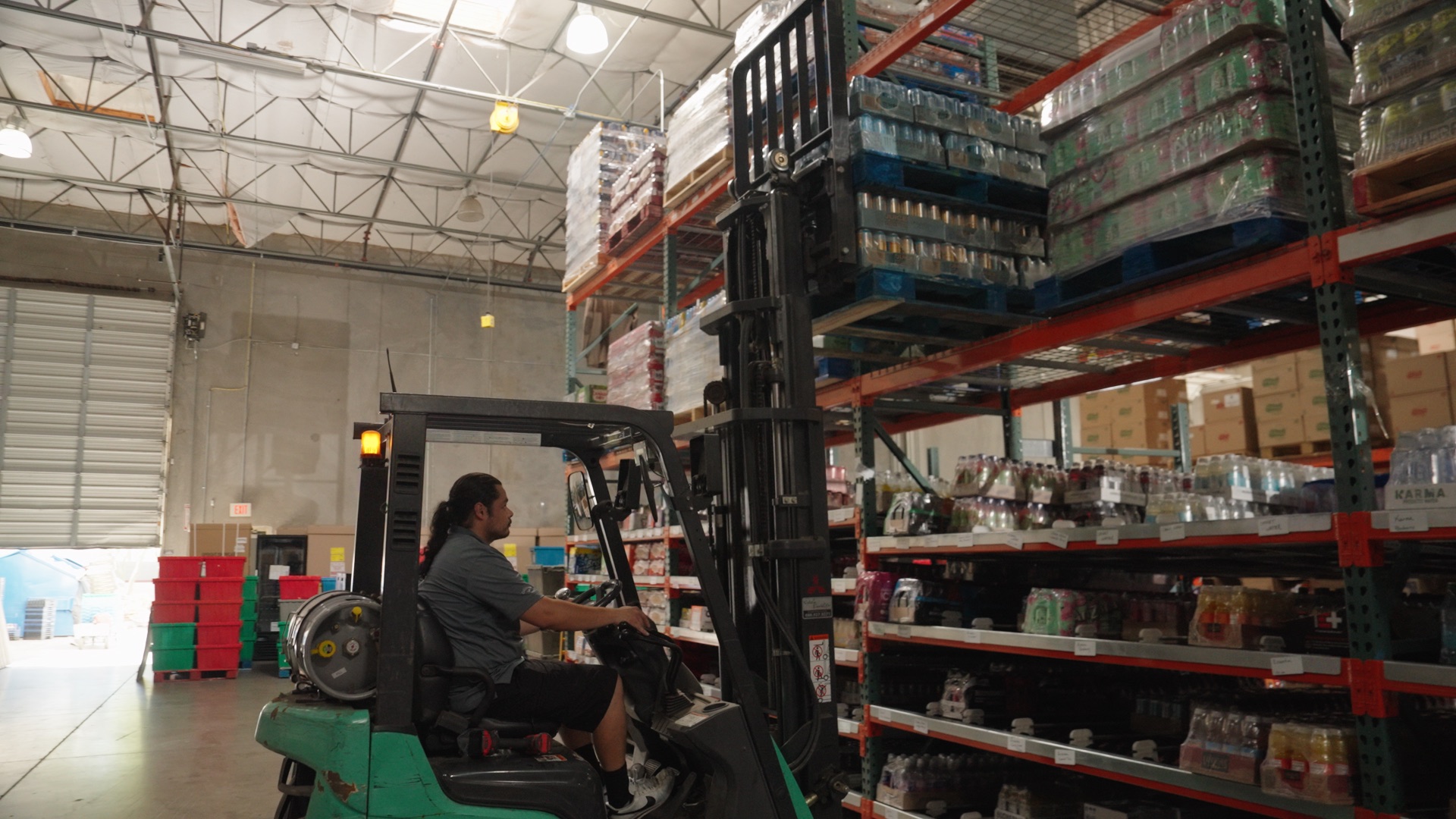 A forklift operator moving pallets of product through the warehouse